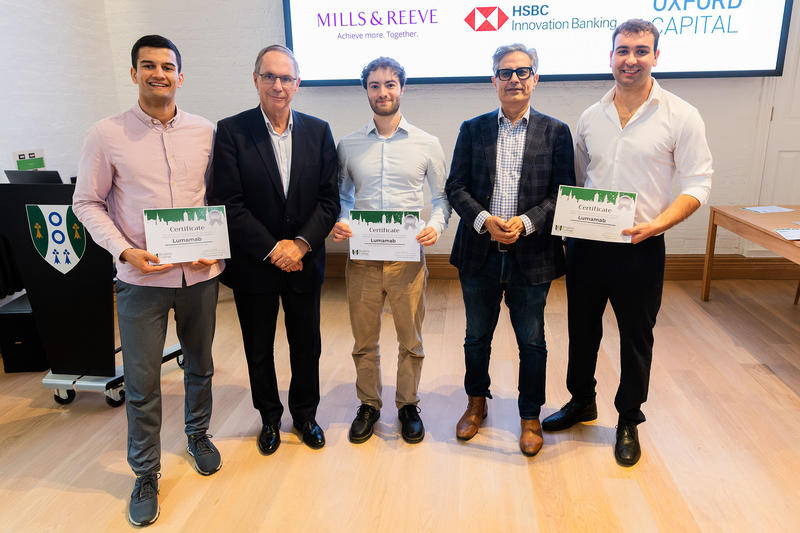 Three young men wearing shirts hold certificates alongside two older men wearing suit jackets.