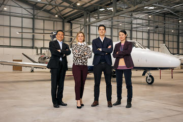 The team behind OXCCU stand in front of a jet plane