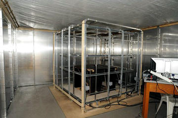 Interior of a large non-magnetic research facility in Oldenburg - magnetic coils and a computer in a metal-lined room.