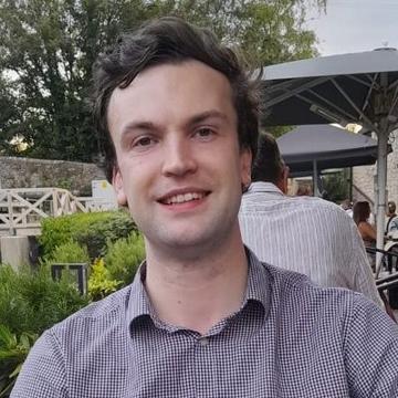Headshot photo of Dr Jamie Wilmore, a man with dark hair wearing a checked shirt.