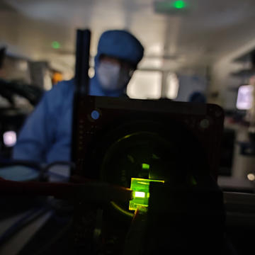 A green coloured OLED in a lab with a researcher standing behind